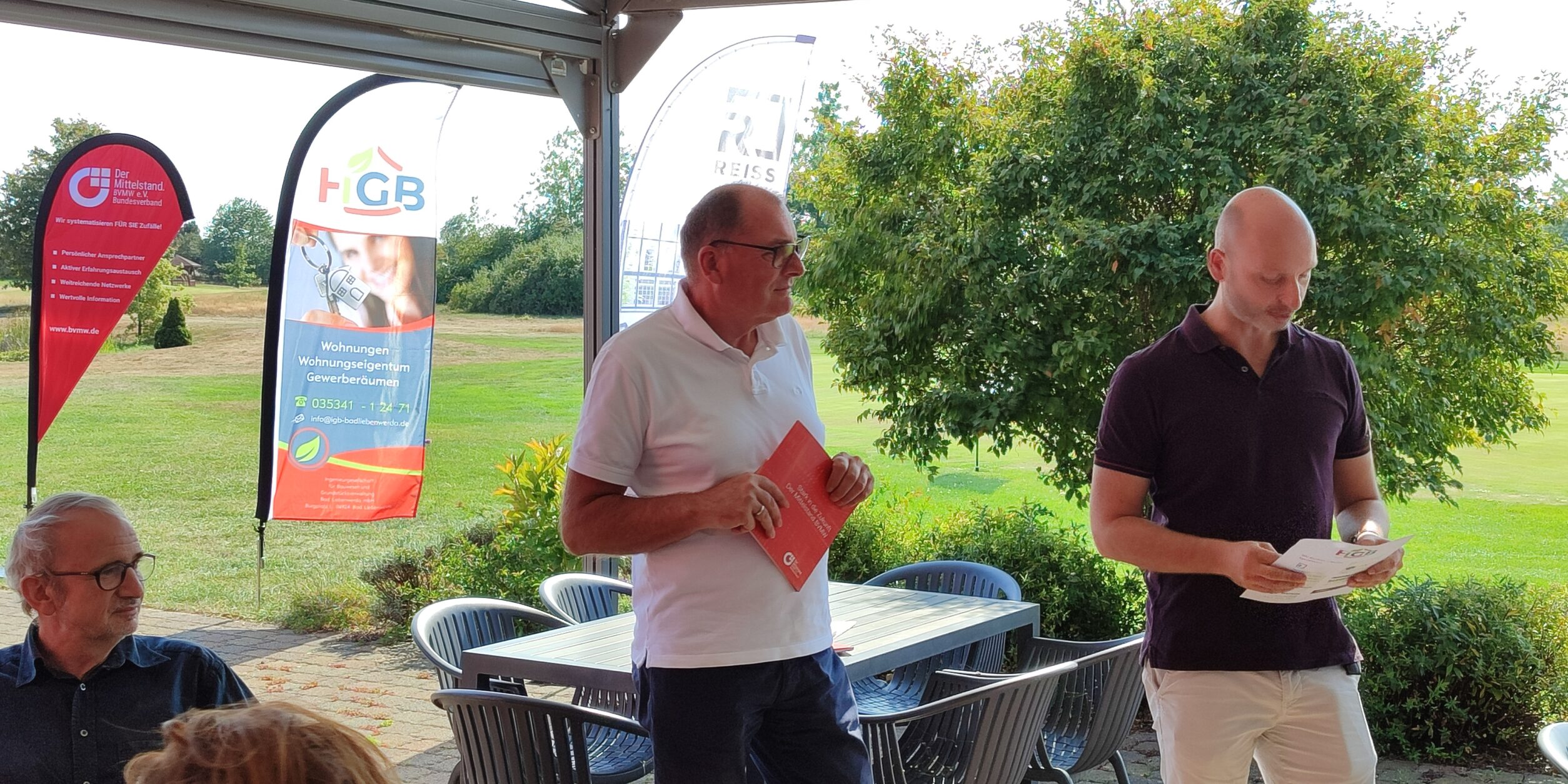 zwei Männer stehen vor Unternehmen*innen und bedanken sich für Ihre Teilnahme am Golf-Cup