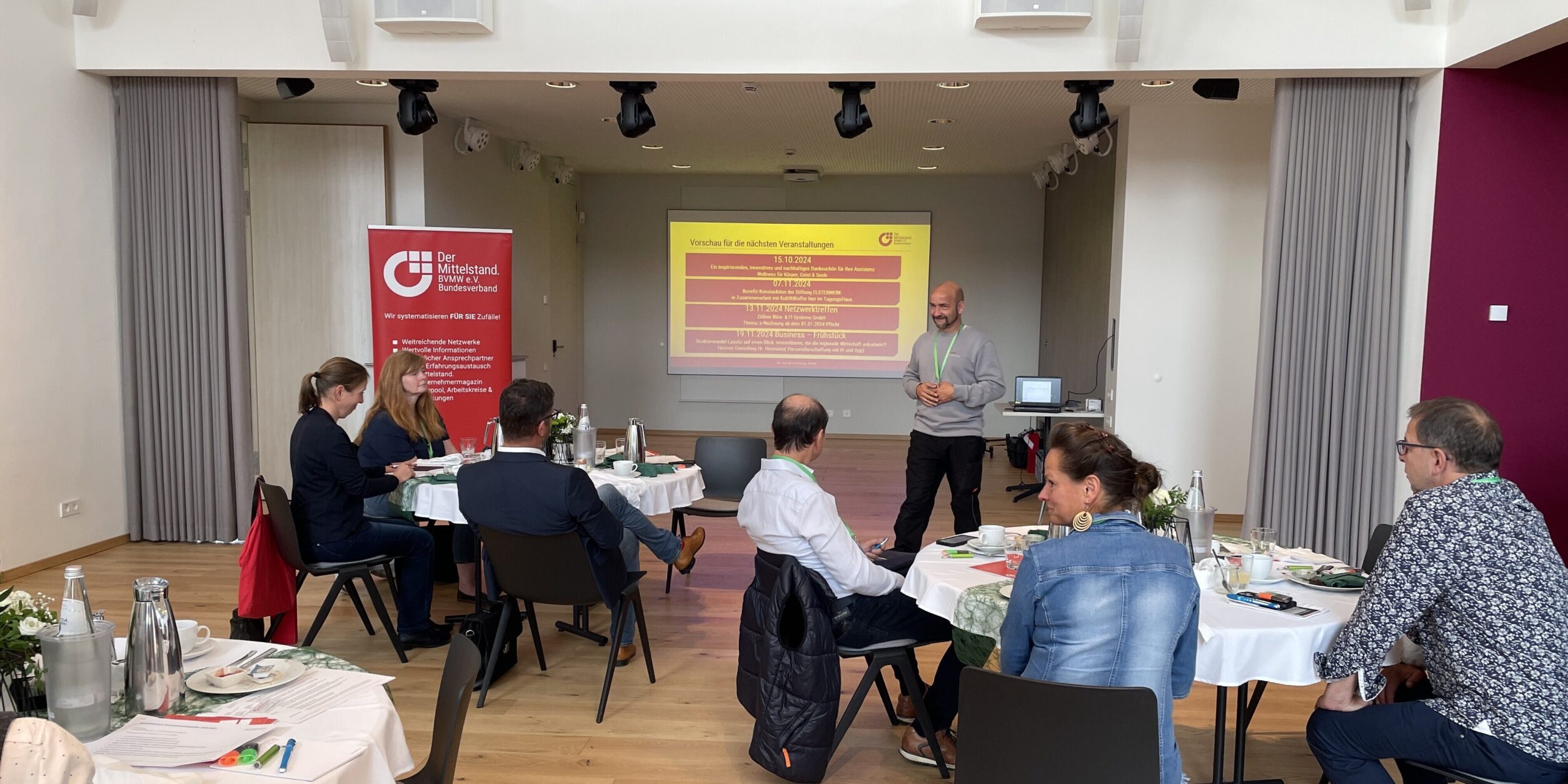 Unternehmer*innen lauschen einem Vortrag während eines Frühstücks