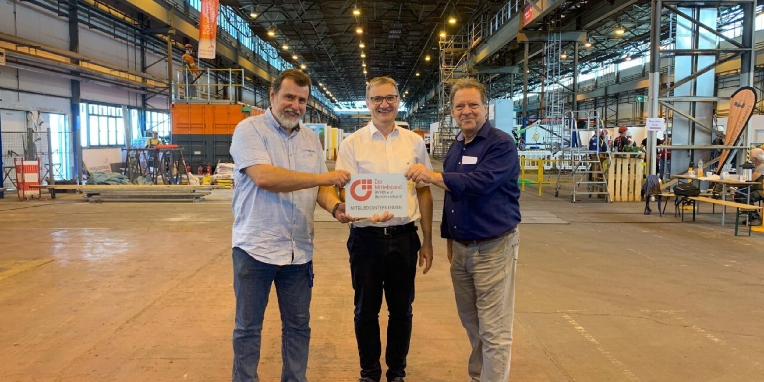 drei Männer halten ein Schild in die Höhe