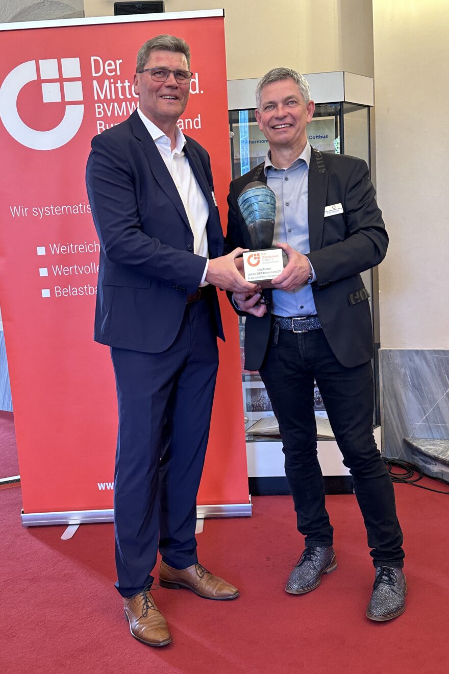 ein Mann überreicht einem anderen eine Preis