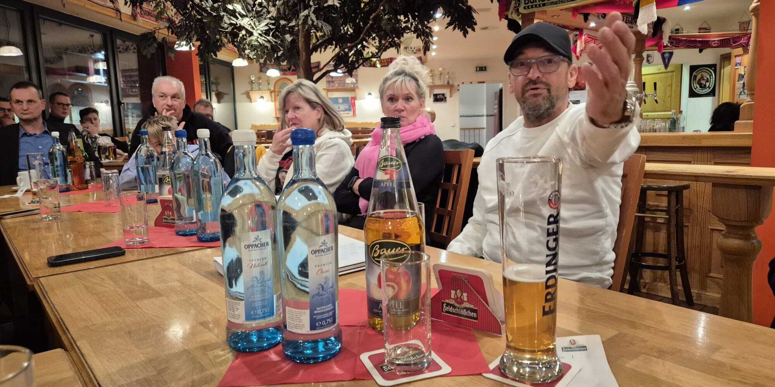 Teilnehmer der Veranstaltung gemeinsam mit FC Energie Cheftrainer Claus Dieter Wollitz am Tisch bei Getränken und lockeren Gesprächen.