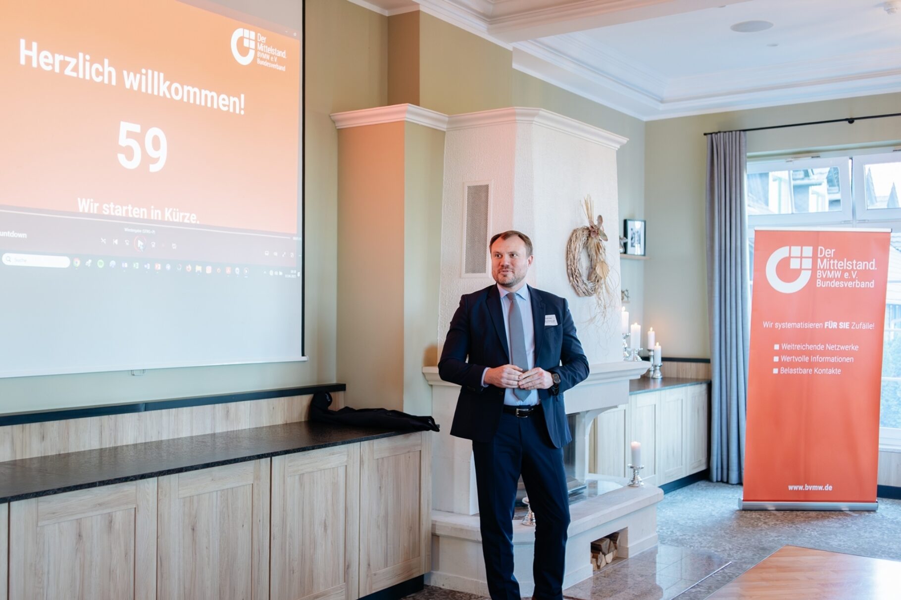 Daniel Keller der Minister für Wirtschaft,  Arbeit, Energie und Klimaschutz vor der Präsentationsleinwand bei der Eröffnung der Veranstaltung.