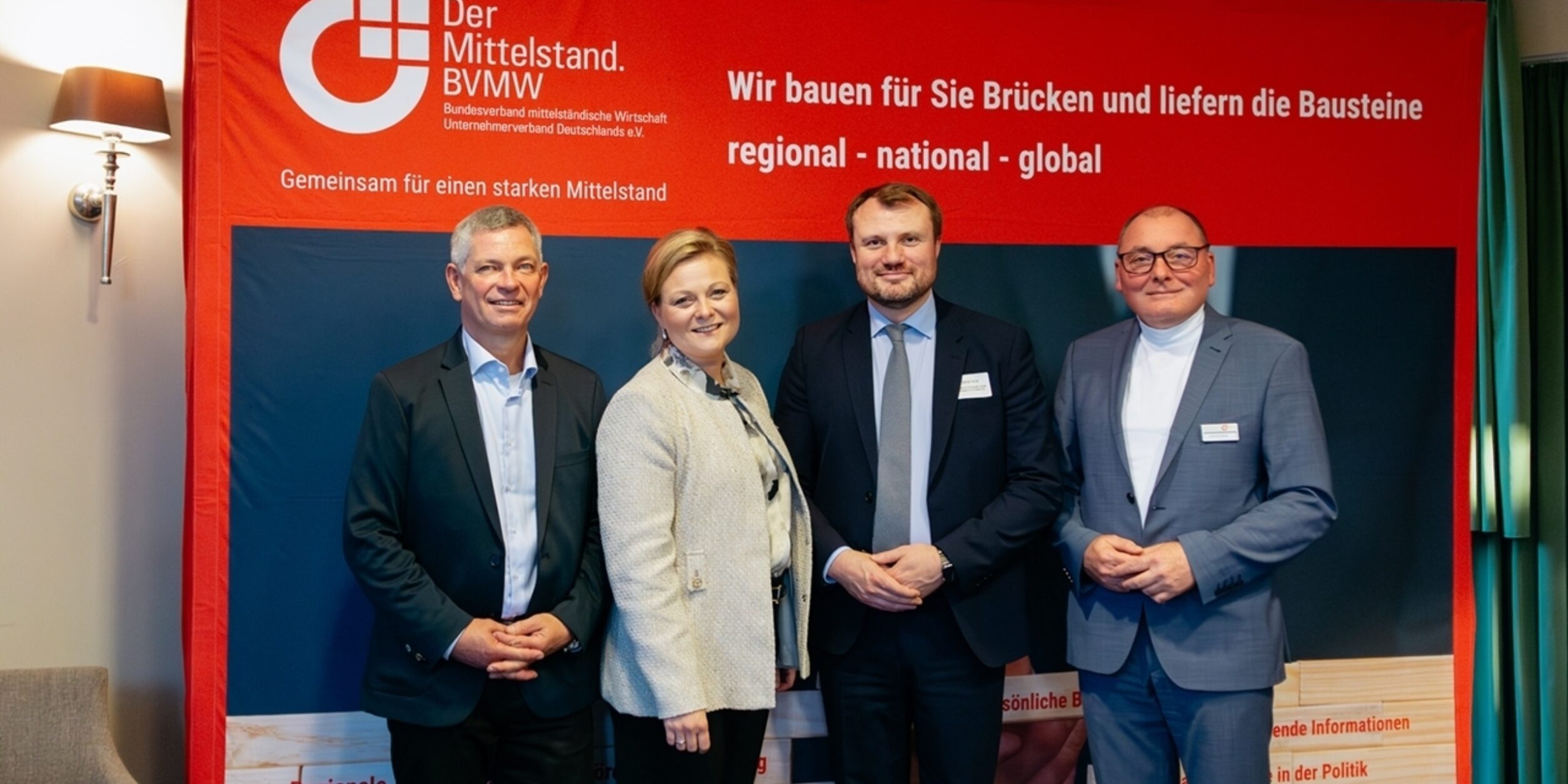 Herr Henkler, Leiter der Wirtschaftsregion Brandenburg Süd-Ost vom BVMW, Frau Nicol Wenke, Geschäftsführerin Christinenhof & Spa, Herr Daniel Keller, Minister für Wirtschaft, Arbeit, Energie und Klimaschutz und Carsten Böhme, Beauftragter des Verbandes Region Elbe-Elster vom BVMW gemeinsam vor einem Plakat des BVMW