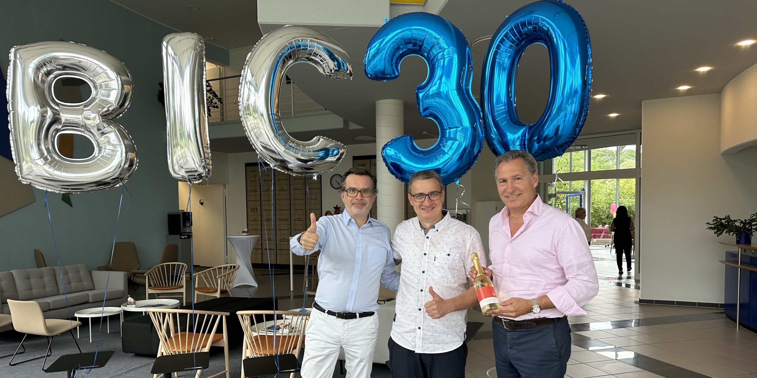ein Mann gratuliert zwei Unternehmern zum 30. Jubiläum