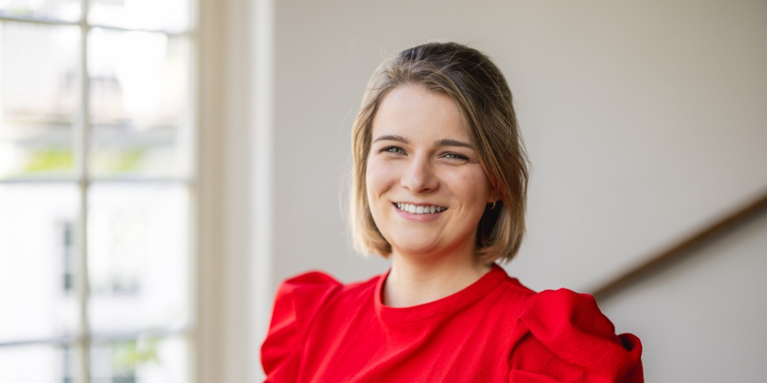 Nele Hobohm in einem roten Kleid vor einem Fenster