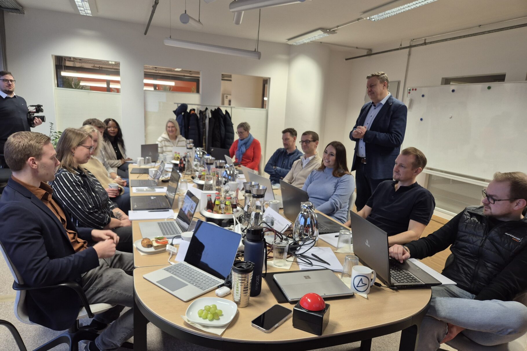 Workshop-Teilnehmende sitzen mit ihren Laptops zusammen an einem großen Tisch