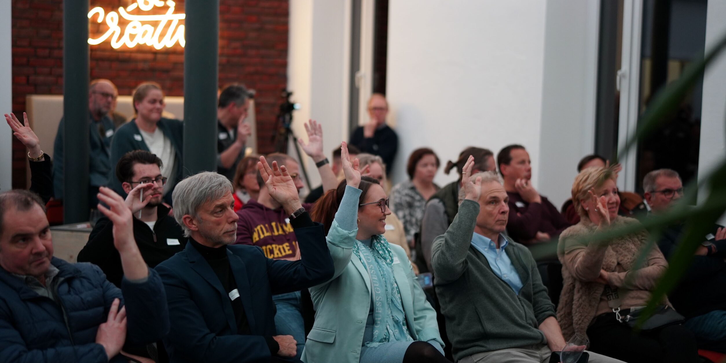 Publikum das eine Hand hebt um abzustimmen