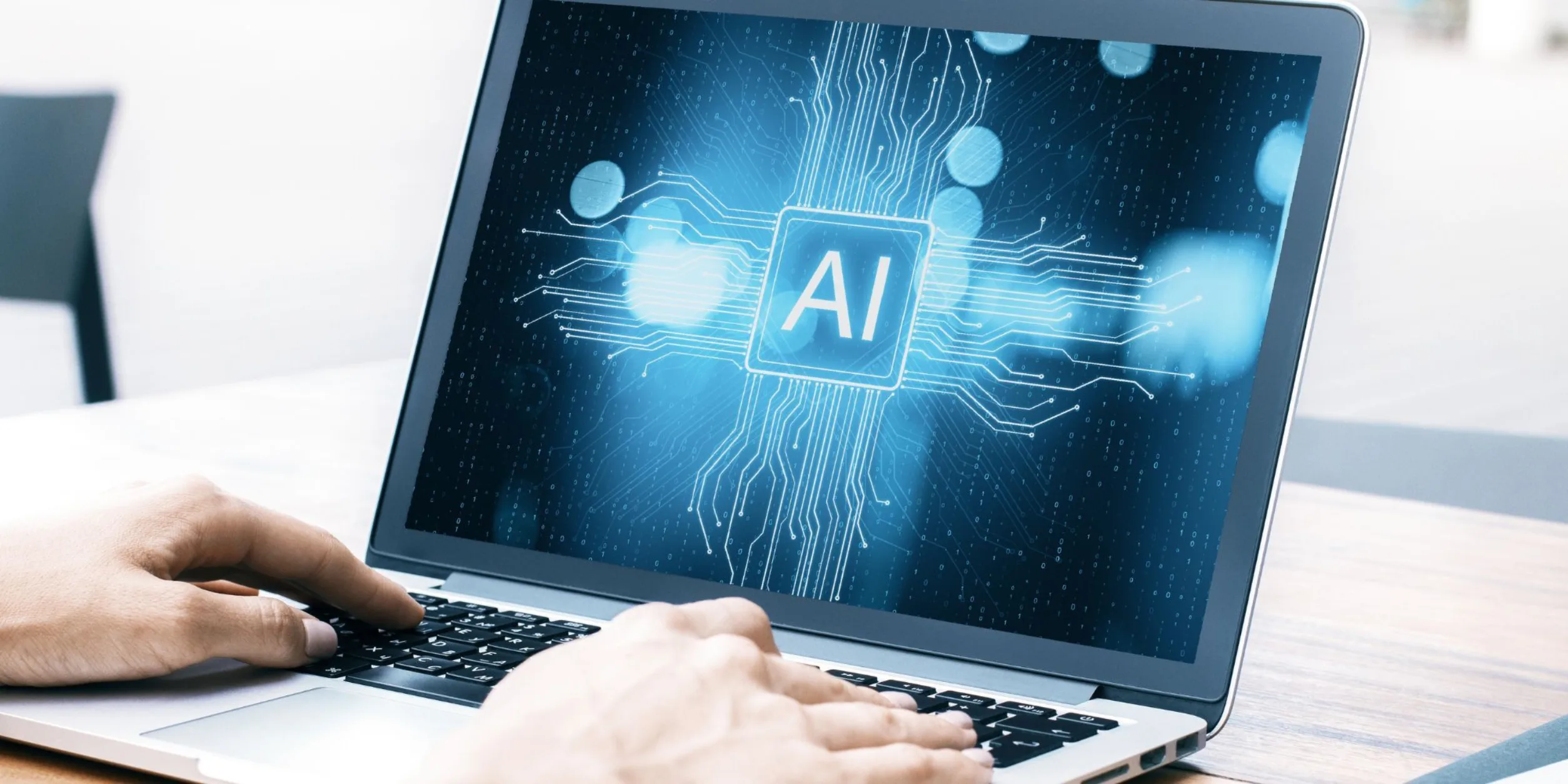 Laptop, Hände auf Tastatur, Schrift "AI" auf dem Bildschirm