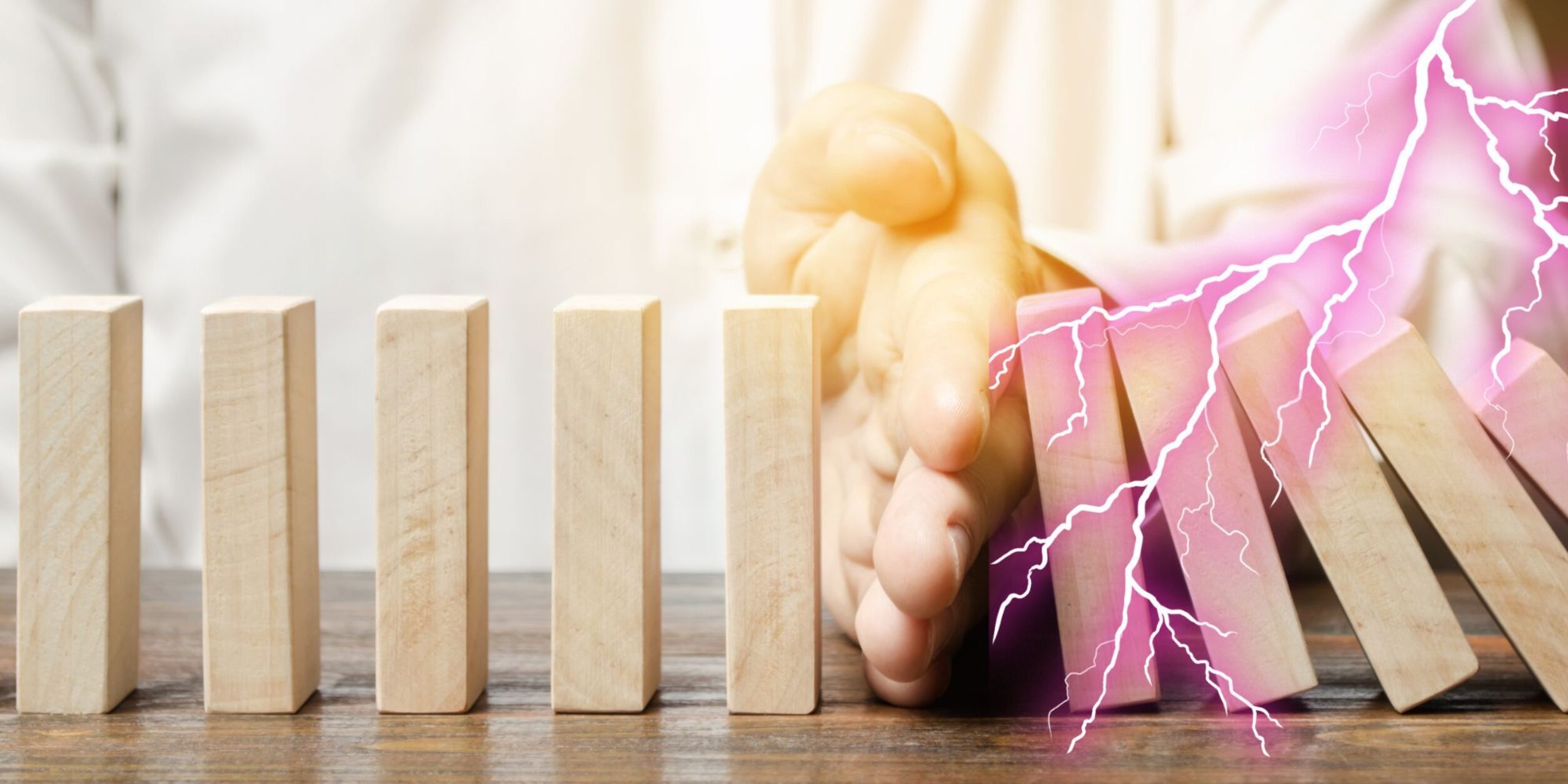 Hand hindert Dominosteine am Umfallen, Blitz schlägt in fallende Steine ein