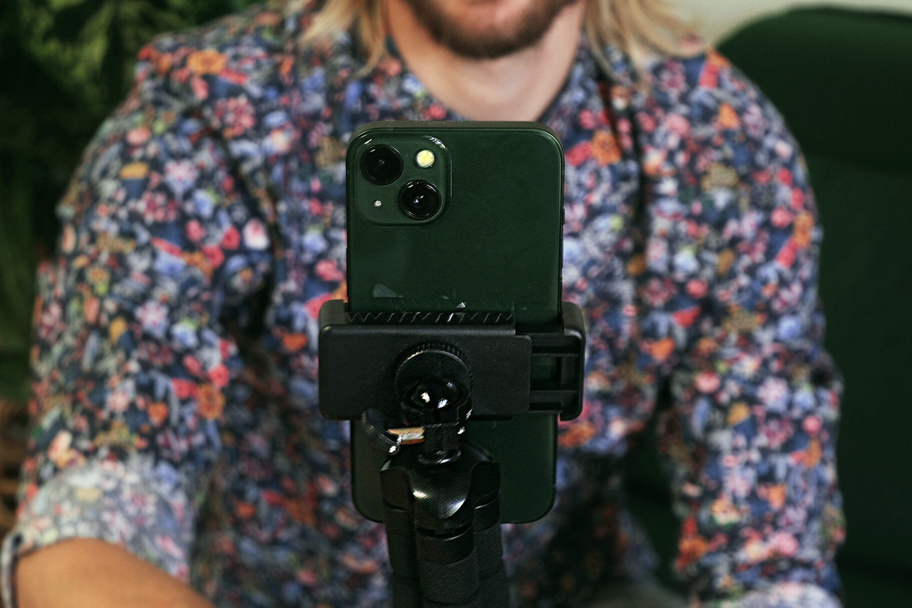 Blick auf ein Handy dass auf einem Stativ befestigt ist und eine Person dahinter steht bei der Contentproduktion