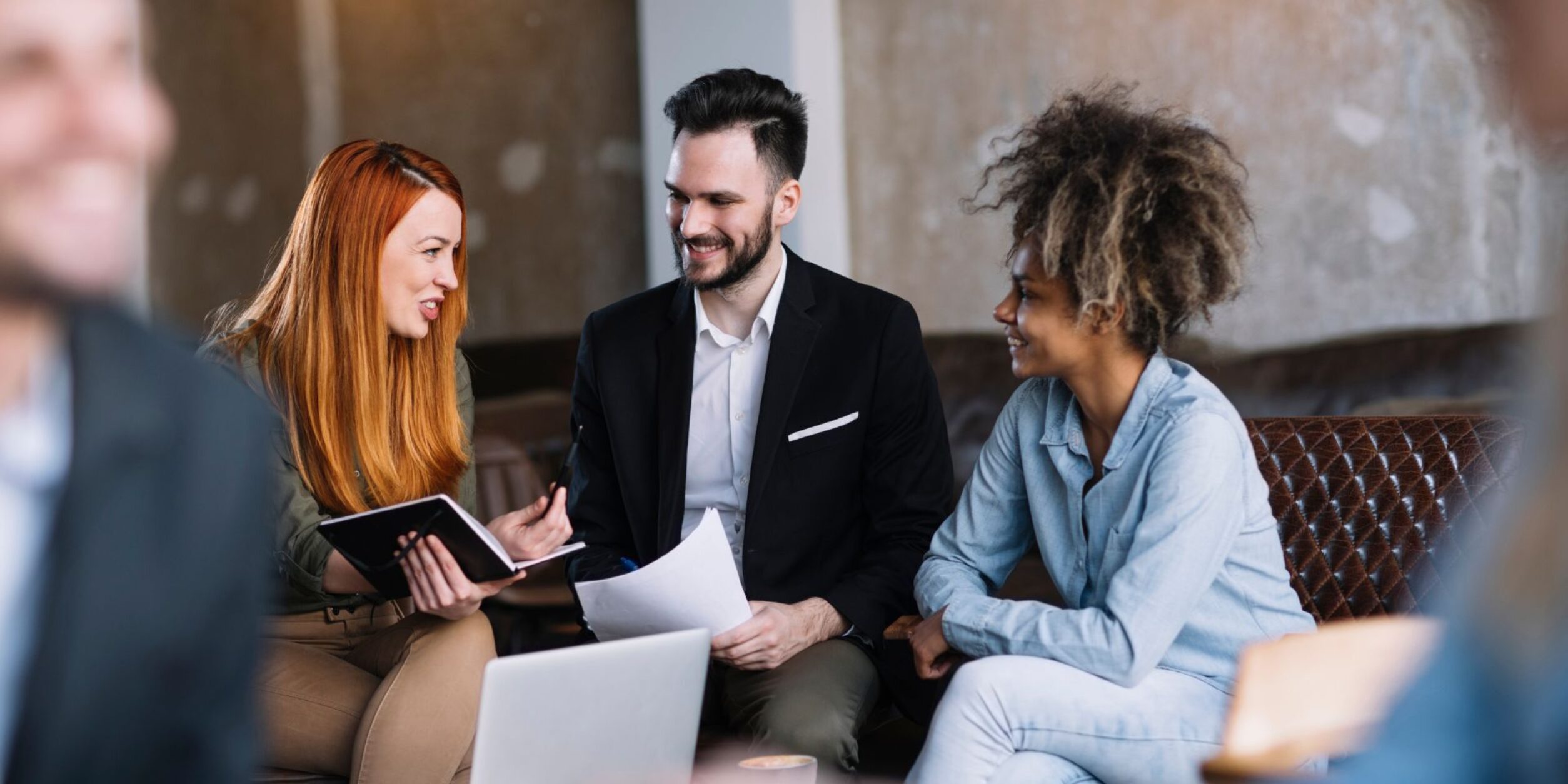 Ein junger Unternehmer bespricht sich mit 2 jungen Unternehmerinnen