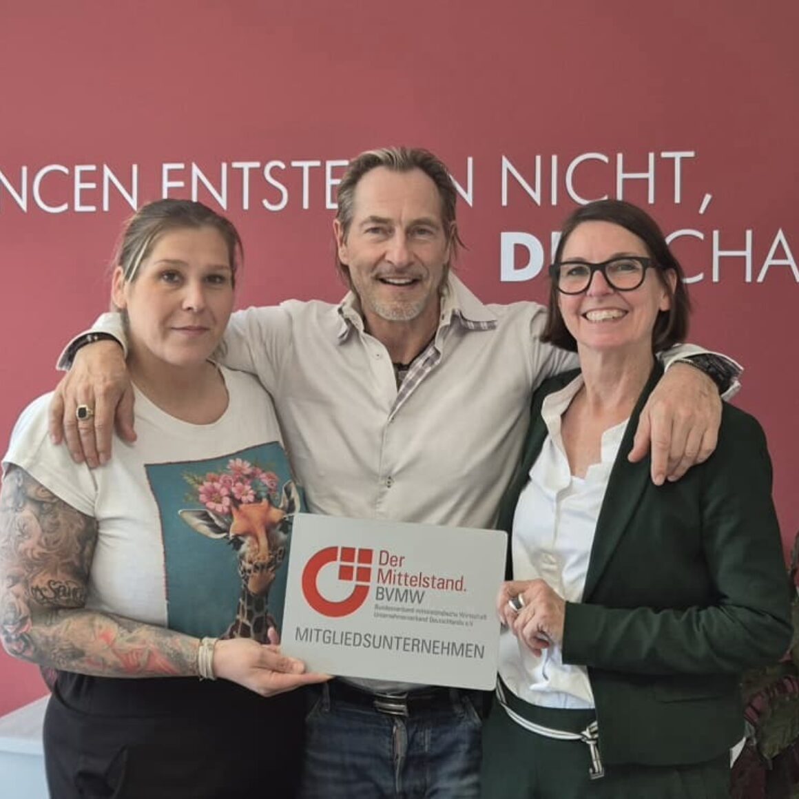 3 Personen bei der Übergabe des BVMW Mitgliedsschildes - Denise Fernandez Diaz, Jürgen Aurin, Anja Merl
