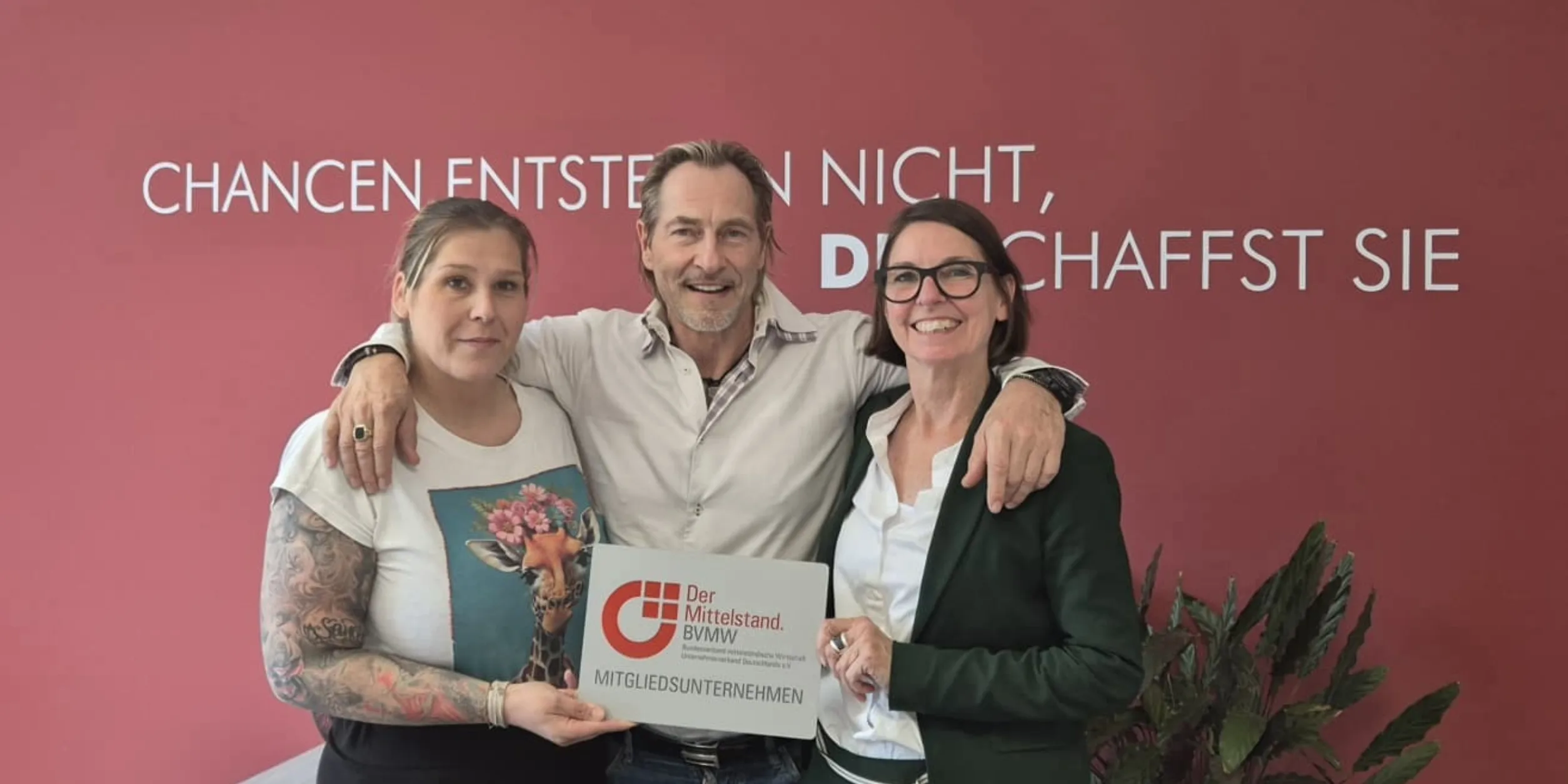 3 Personen bei der Übergabe des BVMW Mitgliedsschildes - Denise Fernandez Diaz, Jürgen Aurin, Anja Merl