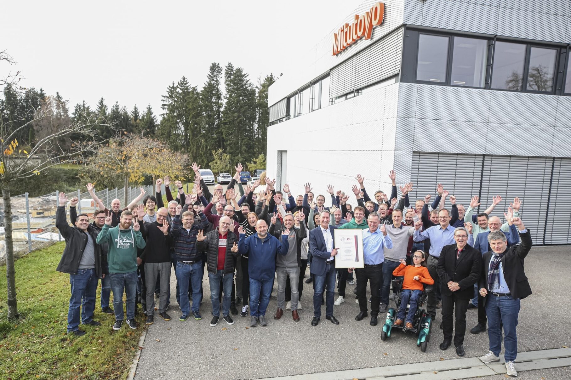 Die Belegschaft von Mitutoyo freut sich bei der Siegelübergabe über die goldwürdigen Ergebnisse.