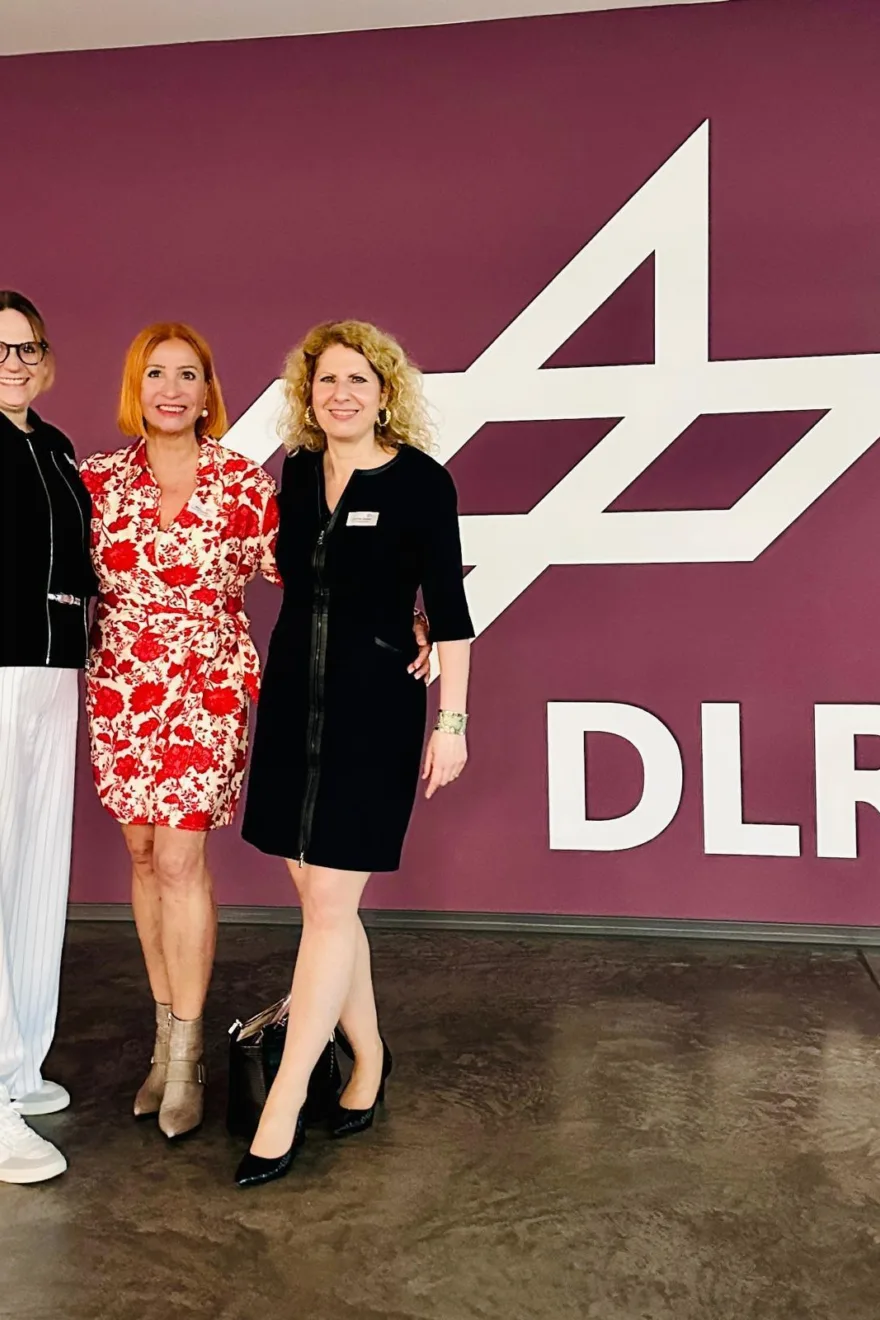 Margit Schmitz mit zwei Referentinnen vor DLR Logo