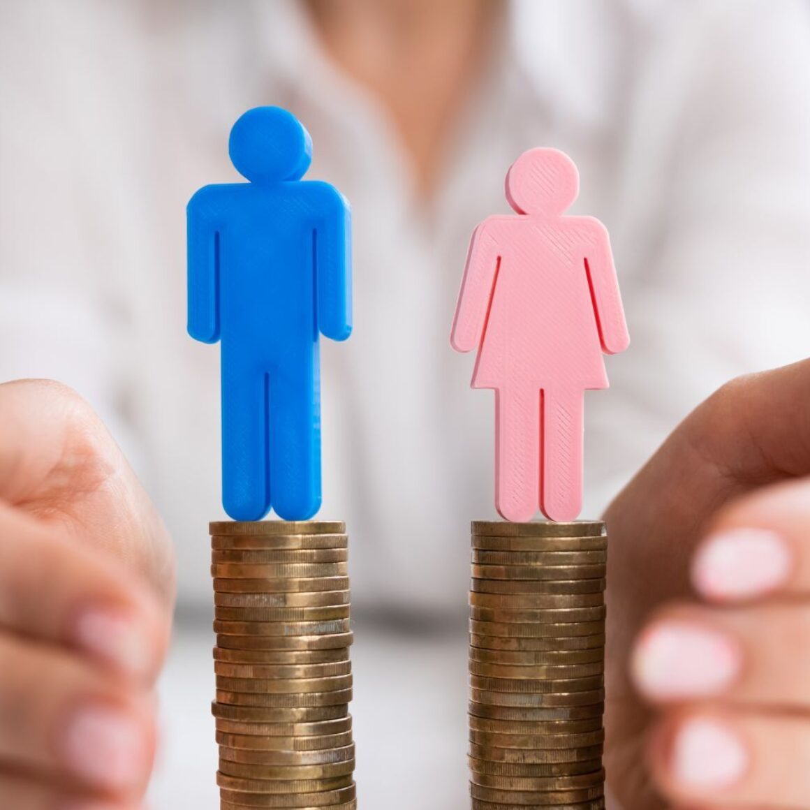 Je ein Symbol für Mann und für Frau stehen auf einem gleichhohen Münzstapel