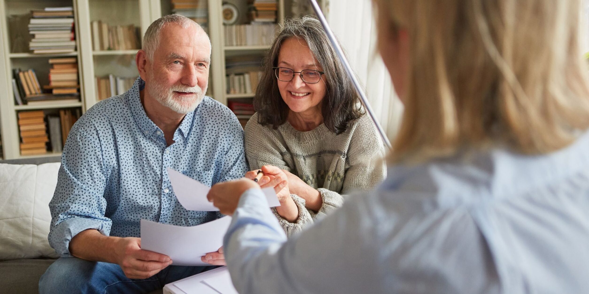 2 ältere Menschen bekommen Unterlagen von einer Beraterin gezeigt
