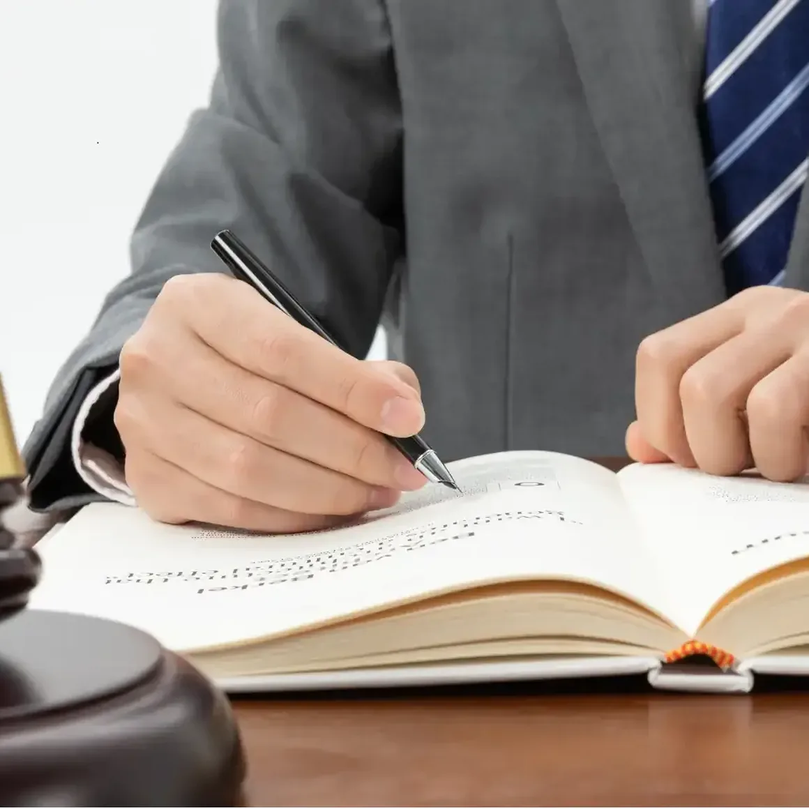 Ein Mann im Anzug schreibt mit Füllfederhalter in ein großes Buch