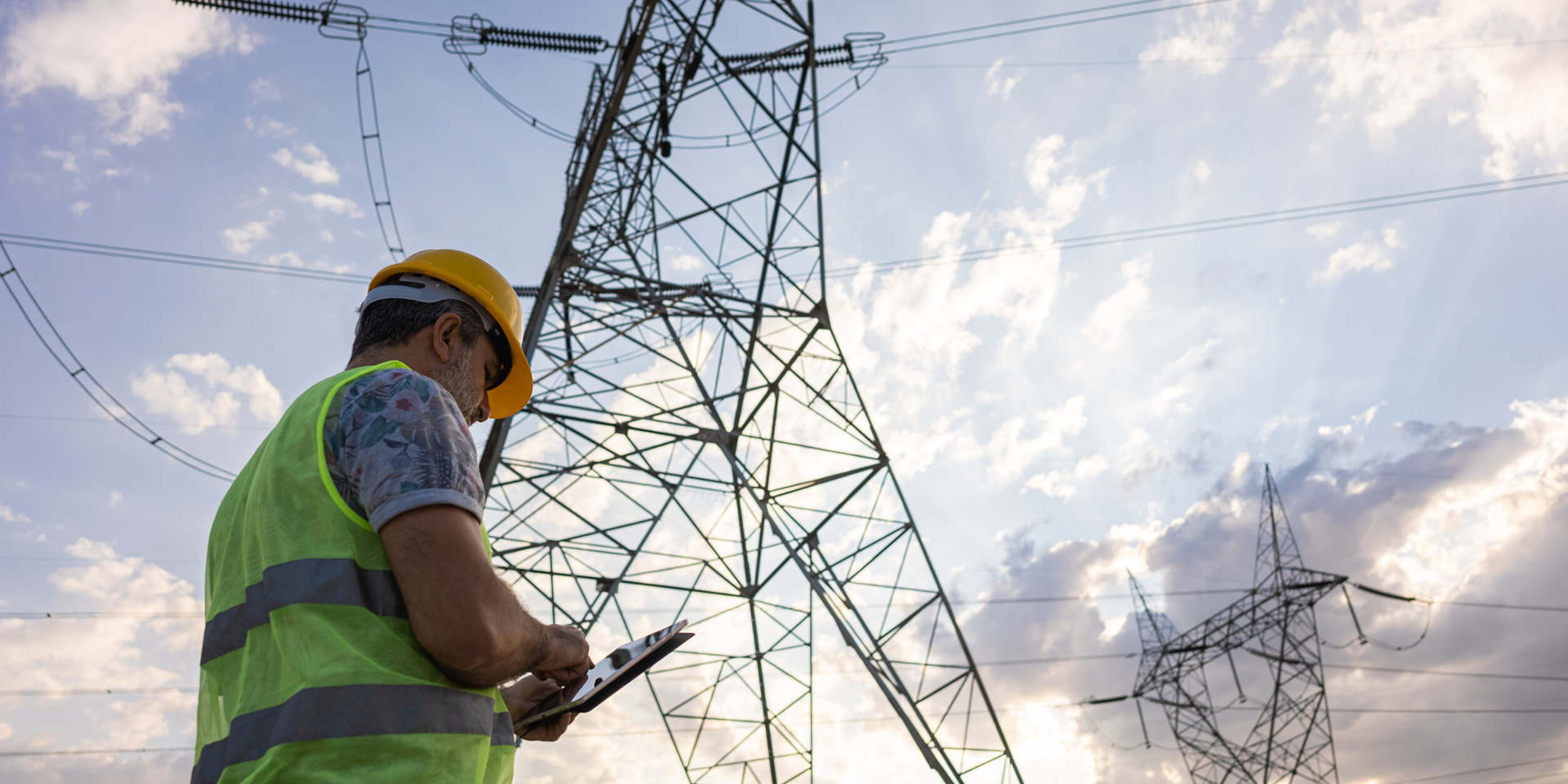 Ein Arbeiter steht vor einem Strommast