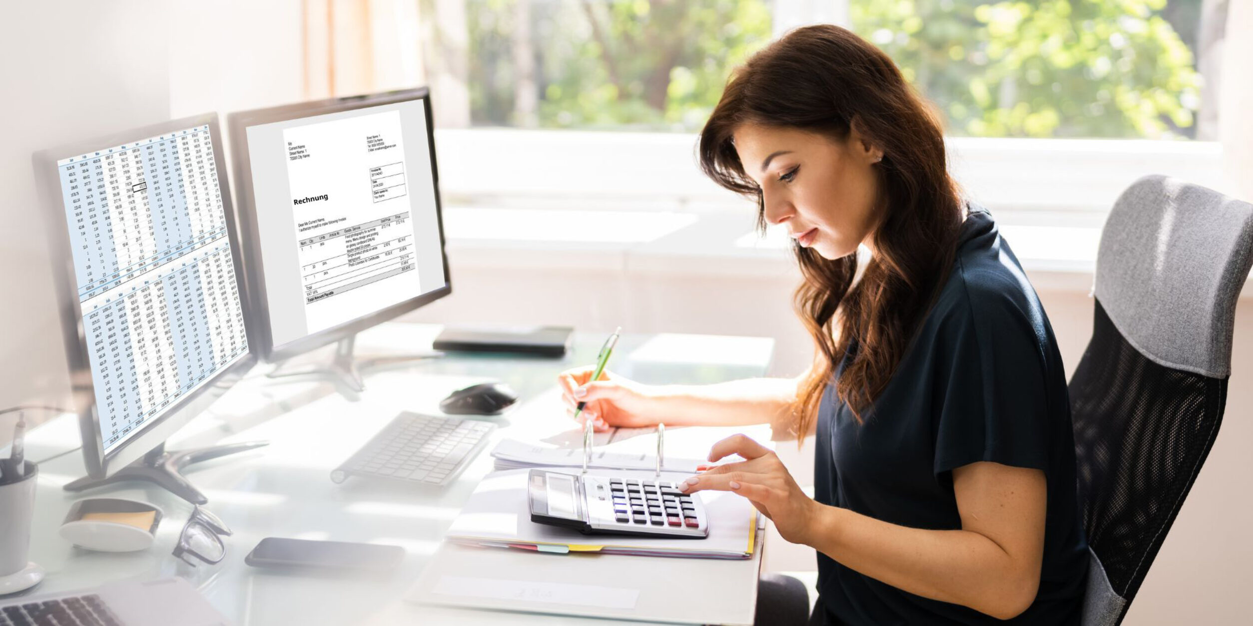 Eine Frau sitzt vor zwei Bildschirmen, auf denen eine E-Rechnung und daneben eine Tabelle mit Finanzdaten geöffnet ist