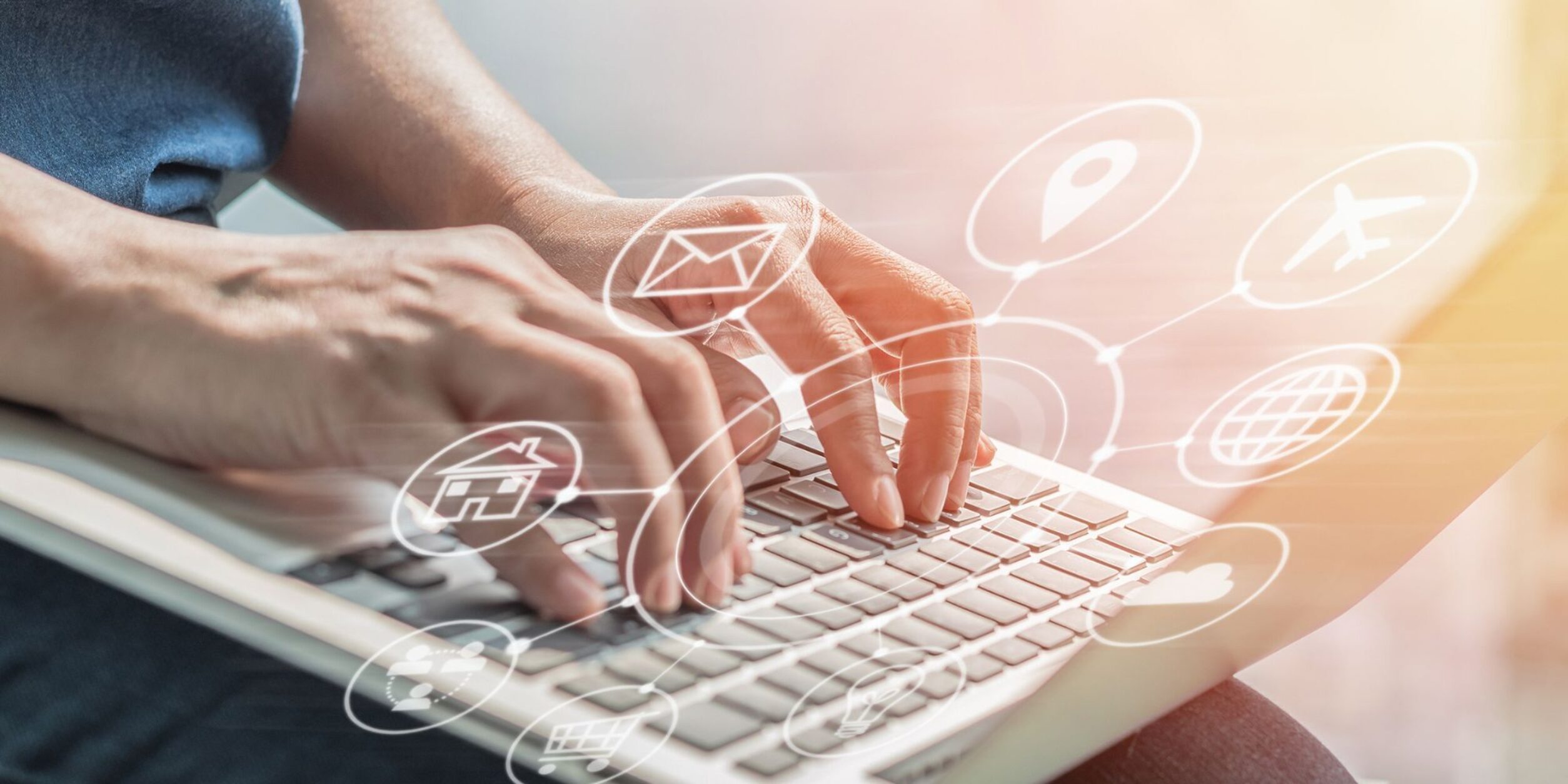 Eine Person bedient die Tastatur eines Laptops aus dem virtuelle Icons hervorkommen