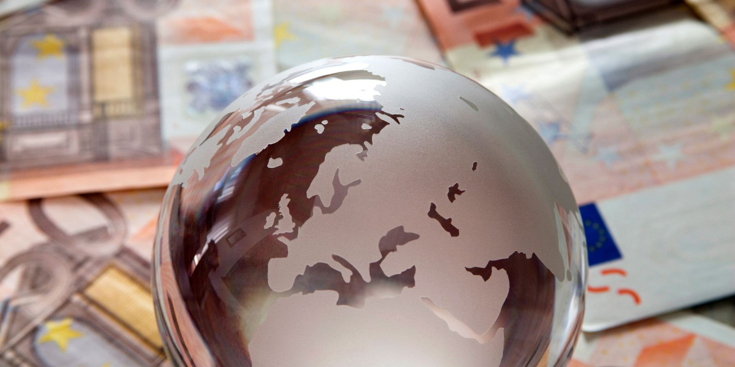 Ein Globus aus Glas liegt auf mehreren Geldscheinen