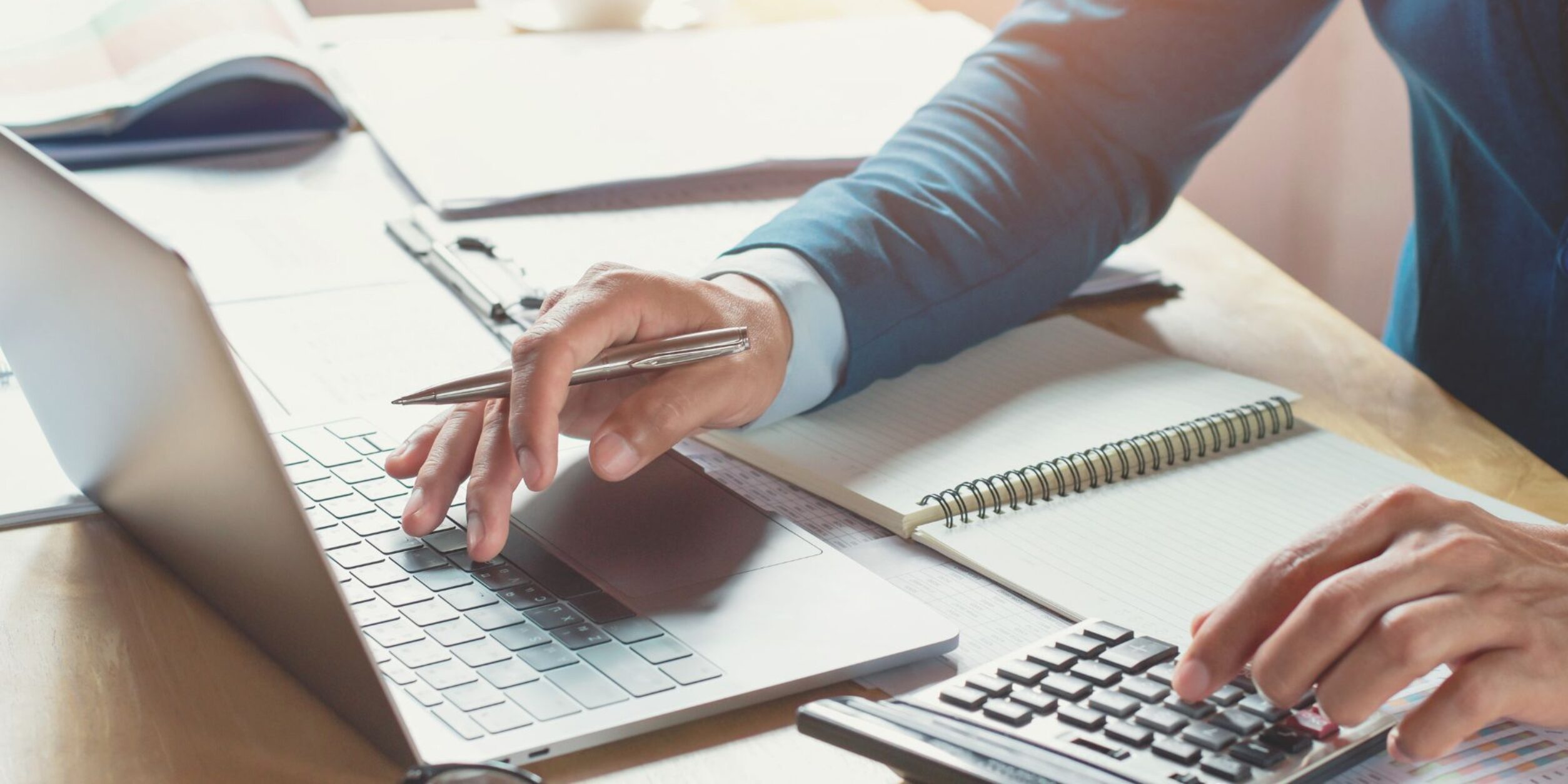 Eine Person bedient Laptop und Taschenrechner gleichzeitig