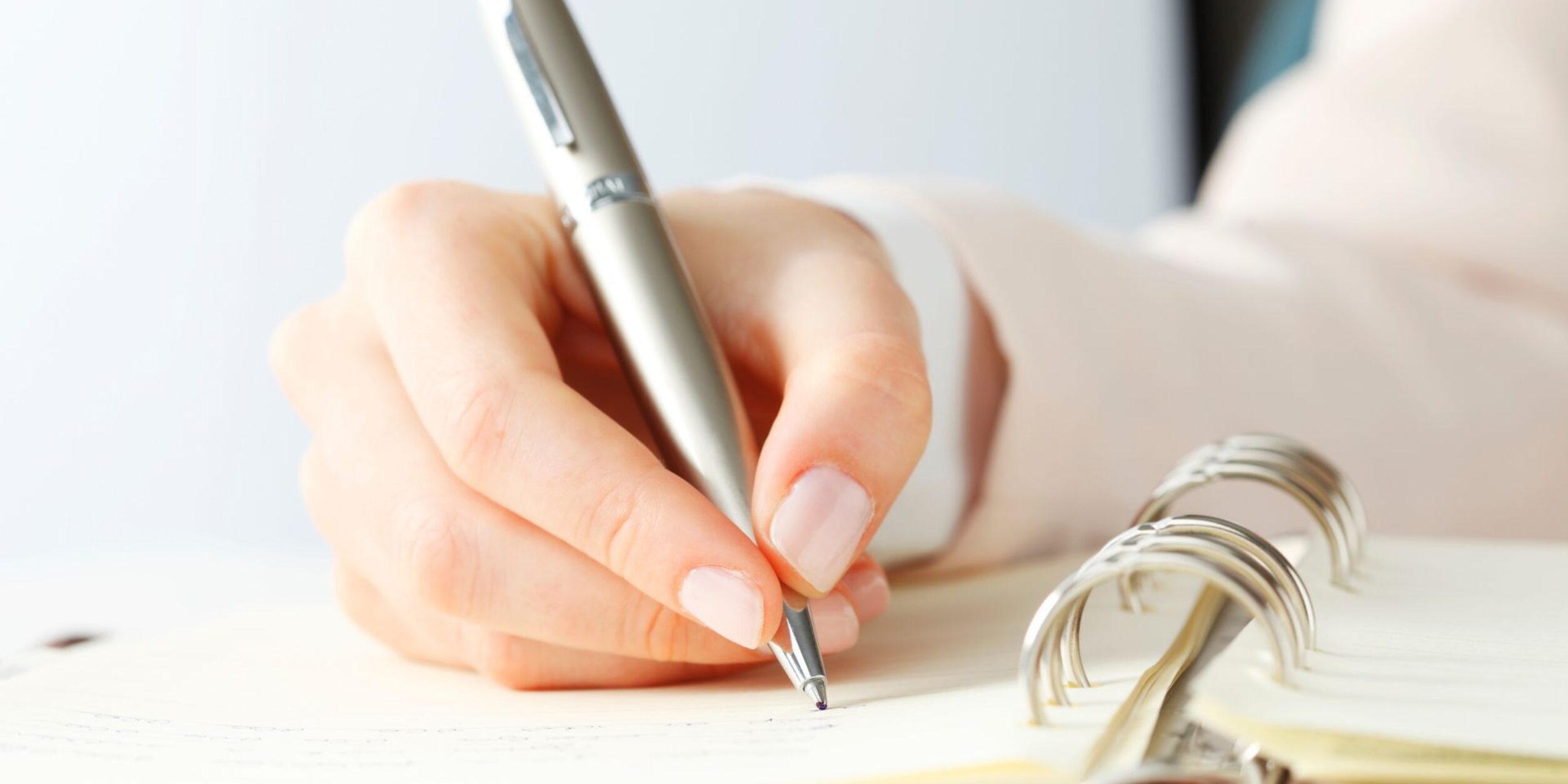 Eine Frau schreibt etwas in ein Ringbuch