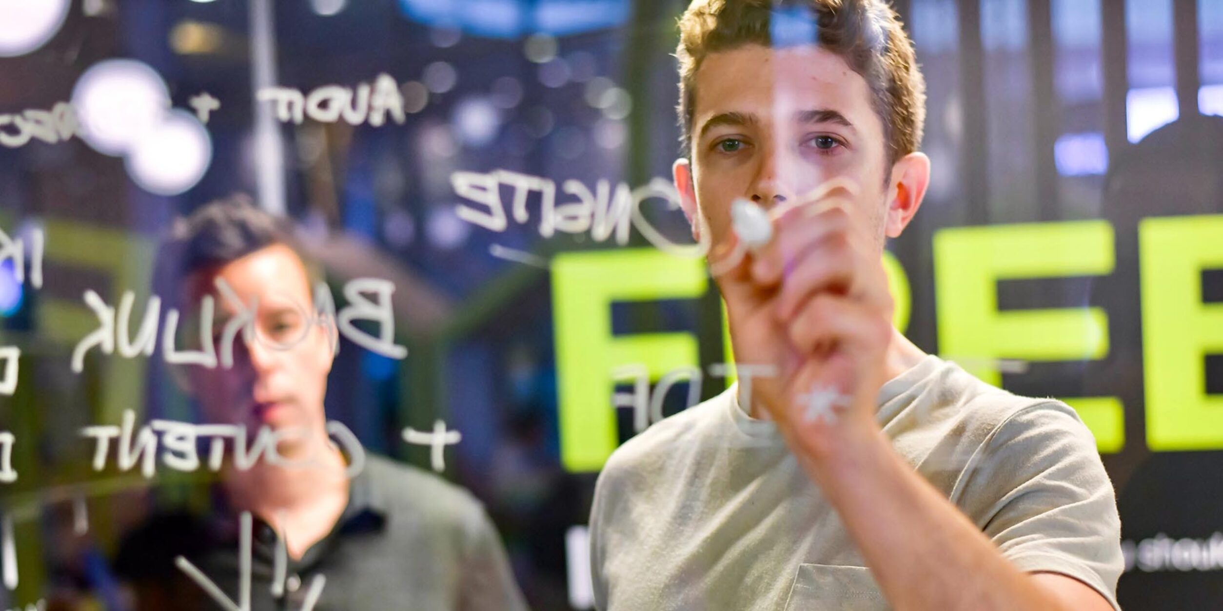 Person schreibt auf eine durchsichtige Tafel